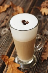 Coffee latte with beans and oak leaves on the table