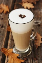 Coffee latte with beans and oak leaves on the table