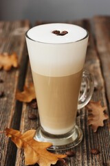 Coffee latte with beans and oak leaves on the table