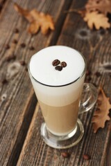 Coffee latte with beans and oak leaves on the table