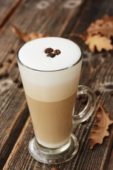 Coffee latte with beans and oak leaves on the table