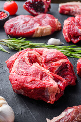 Chuck roll beef steak cuts, with herbs, seasoning  on black table, side view.