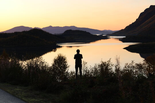 Sunset on Lofoten islands with the silhouette of a man taking pictures 