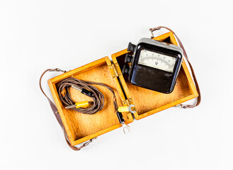a vintage Voltmeter with test leads on a wooden box isolated on a white background