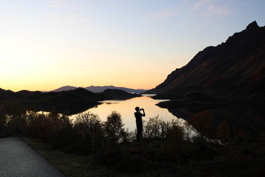 Sunset on Lofoten islands with the silhouette of a man taking pictures 