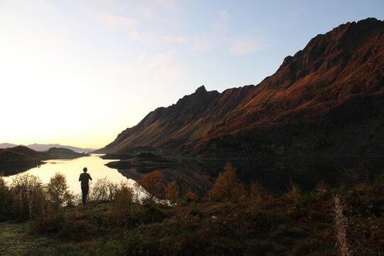 Sunset on Lofoten islands with the silhouette of a man taking pictures 