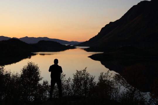 Sunset on Lofoten islands with the silhouette of a man taking pictures 