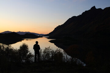 Sunset on Lofoten islands with the silhouette of a man taking pictures 