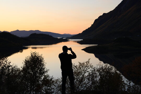 Man taking photos of the sunset on Lofoten islands in Norway