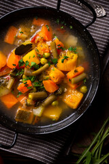 Vegetable soup with parsley on dark background
