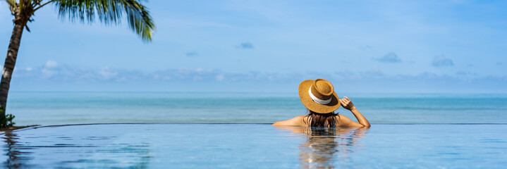 Young woman traveler relaxing and enjoying by a tropical resort pool while traveling for summer...