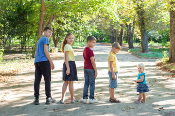 Five children stand in a row in height in the park, walking and