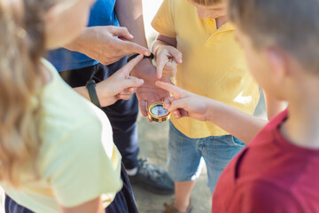 Four children look at the compass and point their fingers in different directions.