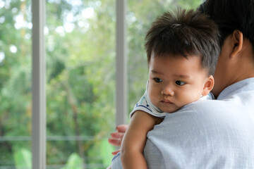 Mother is holding little baby boy in her arms.