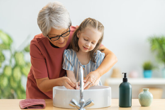 girl and her grandmother are washing hands