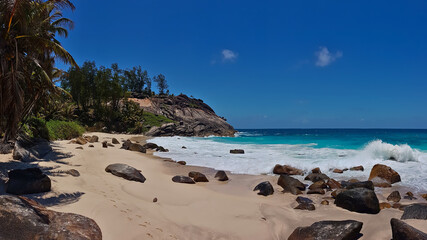 Tropical beach Anse Capucins in the south of Mahe island, Seychelles with footprints in the sand, turquoise colored water and granite rock formations.