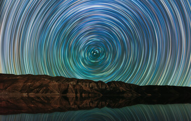 Long exposure night landscape. Beautiful mountains and lake. colorful star trails on the sky. Night...