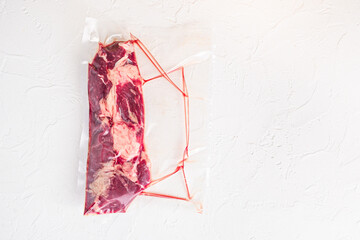 Vacuum packed organic chuck roll steak on white concrete  textured background,top view space for text.