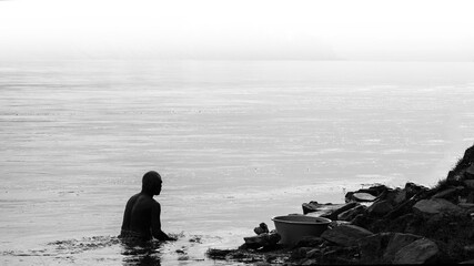 A man taking bath in a flowing river in the misty morning