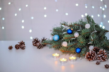 Christmas composition with fir branches, Christmas toys and burning candles, greeting card on the background of a bokeh of lights garland