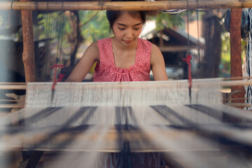 Young women weaving with traditional Thai weaving machine