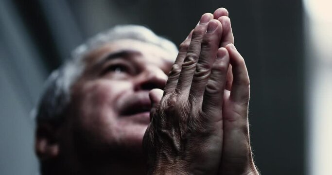 Dramatic serious older man praying to God