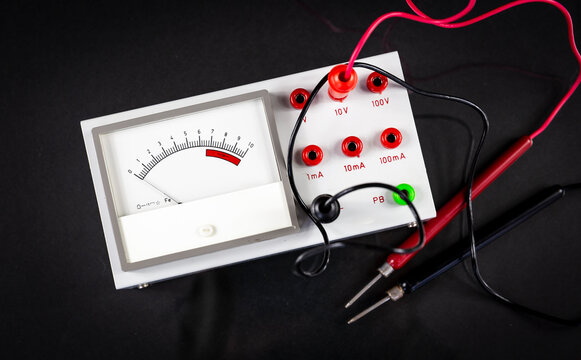 an analog multimeter with test leads - voltmeter and ammeter isolated on a black background