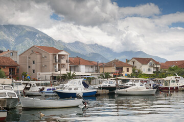 Fototapeta na wymiar Boats and boats in the port against the backdrop of the city and mountains, Tivat, Montenegro.