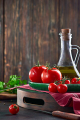 Ripe fresh red tomatoes on a tray with a bottle of olive oil.