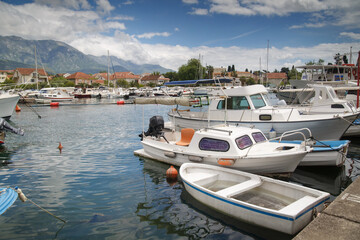 Fototapeta na wymiar Boats and boats in the port against the backdrop of the city and mountains, Tivat, Montenegro.