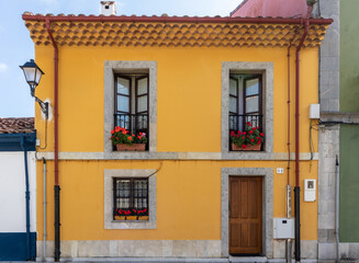 Traditional Spanish house. Old building restored, facade painted in yellow. Windows and balcony...