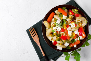 Pasta salad with green beans, baby carrots, bell pepper, corn and feta cheese. Mediterranean cuisine meal. Top view