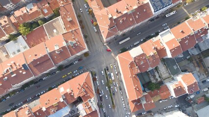 Aerial view of the city traffics at the center. Vehicles are moving on the road between buildings.