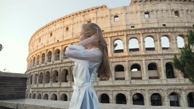 Beautiful girl is photographed in Rome near the Colosseum. A girl makes a selfie. She is smiling and posing. Sunset. 4k