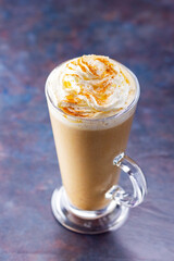 Pumpkin latte on a dark background. Pumpkin spice latte with whipped cream. Autumn drink. Minimalism. Copy space