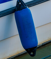 Blue fender buoy hanging of the side of a ship. Close up.