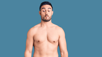 Fototapeta premium Young handsome man wearing swimwear making fish face with lips, crazy and comical gesture. funny expression.