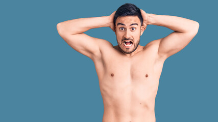 Fototapeta premium Young handsome man wearing swimwear crazy and scared with hands on head, afraid and surprised of shock with open mouth