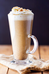Pumpkin latte on a wooden background. Pumpkin spice latte with whipped cream on a burlap. Minimalism