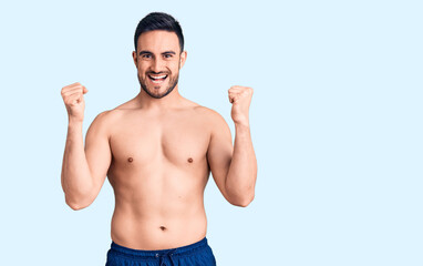 Fototapeta premium Young handsome man wearing swimwear screaming proud, celebrating victory and success very excited with raised arms