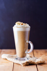 Pumpkin latte on a wooden background. Pumpkin spice latte with whipped cream on a burlap. Minimalism