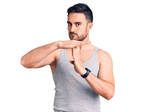 Young handsome man wearing swimwear and sleeveless t-shirt doing time out gesture with hands, frustrated and serious face