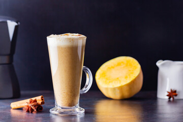 Pumpkin spice latte, coffee maker and milk jug on a dark background. Pumpkin latte with whipped...