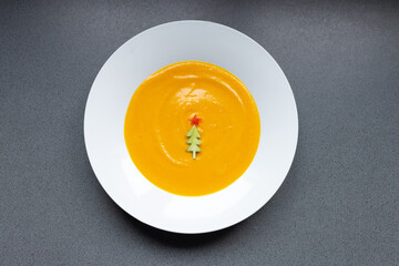 pumpkin soup decorated with christmas tree shaped cucumber, top view
