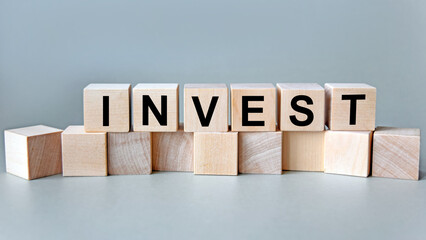 The inscription invest on wooden cubes isolated on a light background, the concept of business and finance.