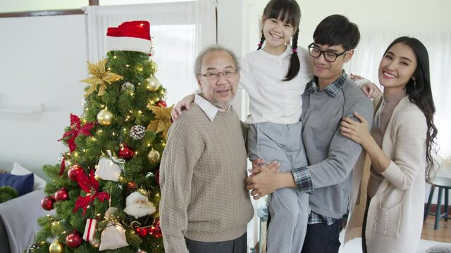 Portrait of happy asian three generation family in quarantine merry christmas enjoy take photo shoot group shot standing together at home apartment enjoy leisure time with X'mas tree.