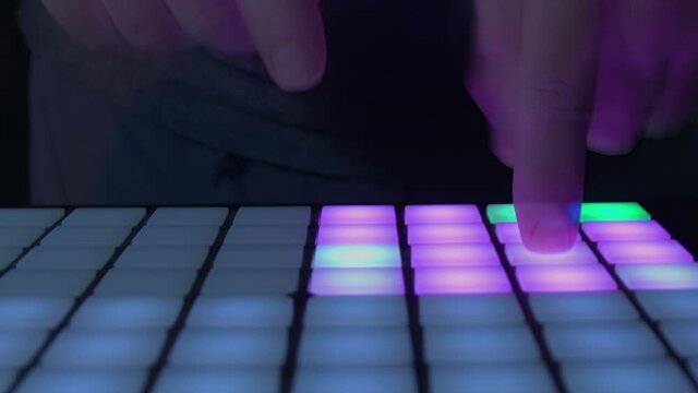 Close up of fingers playing pads on a digital controller in the studio