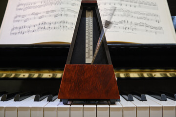 Metronome in motion on a piano with a music sheet in background