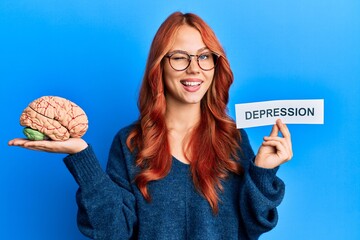Young redhead woman holding brain and depression text winking looking at the camera with sexy...