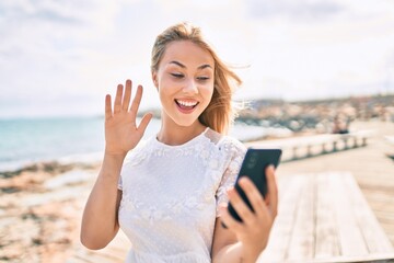 Young caucasian girl smiling happy doing video call using smartphone at street of city.